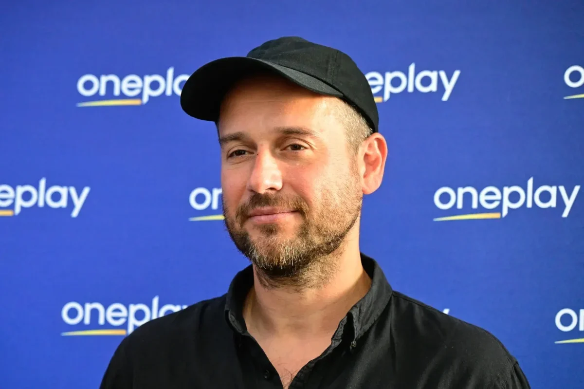 Muž stojí před nápisy Oneplay.