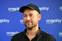 Muž stojí před nápisy Oneplay.