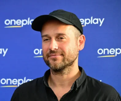 Muž stojí před nápisy Oneplay.