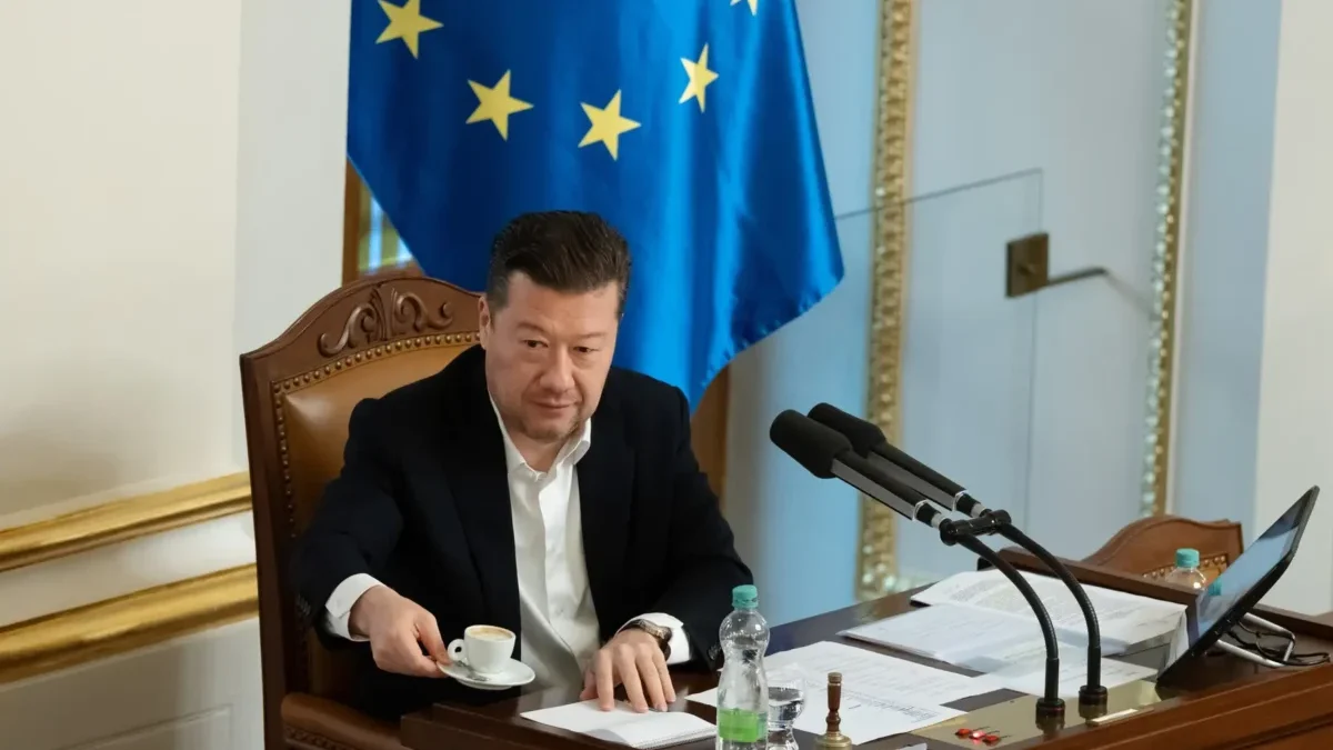 Muž v obleku a za ním vlajka Evropské unie.