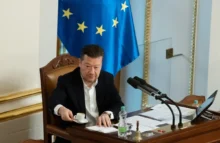 Muž v obleku a za ním vlajka Evropské unie.
