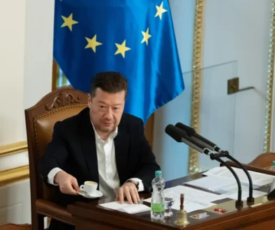 Muž v obleku a za ním vlajka Evropské unie.