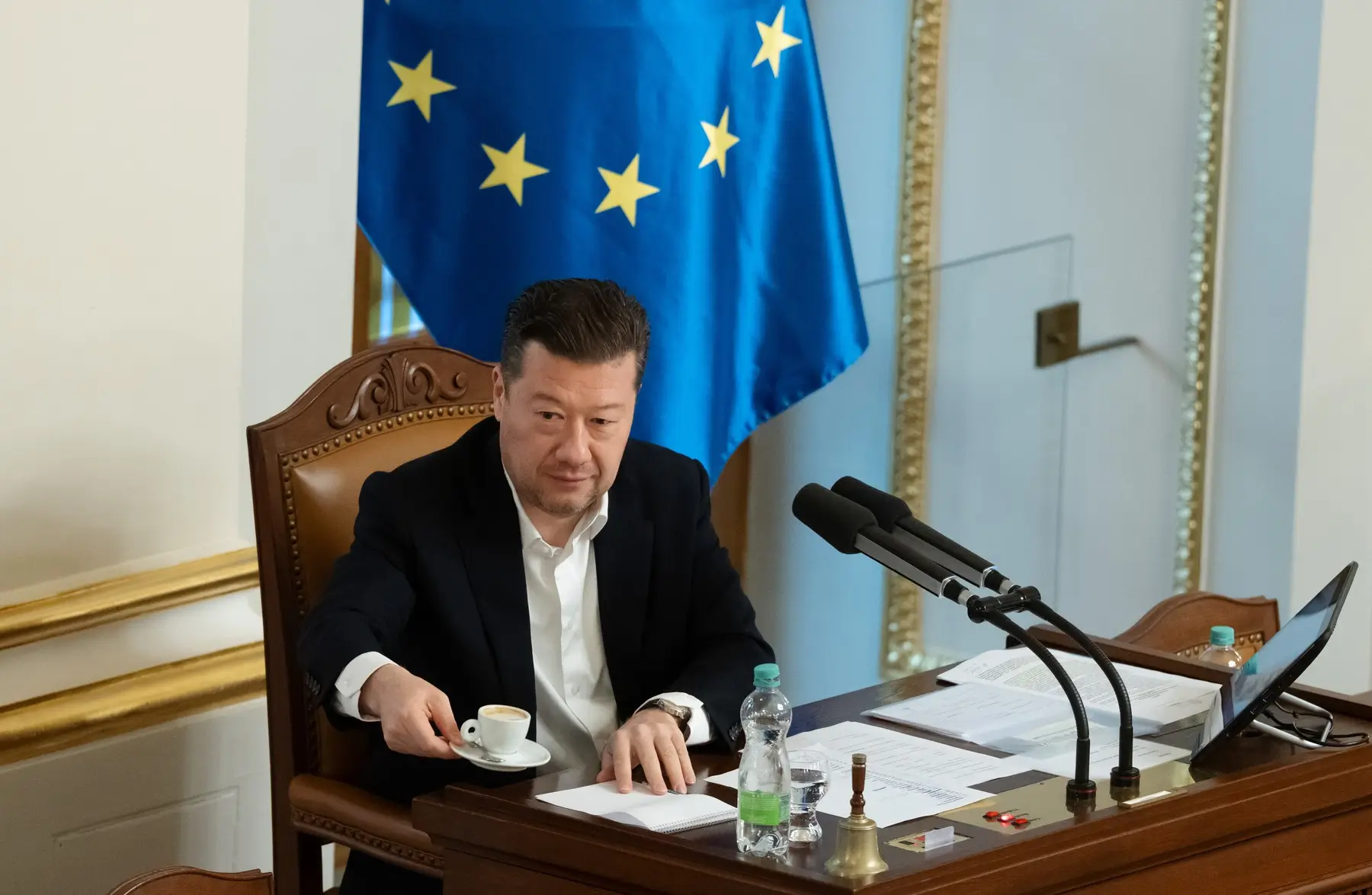 Muž v obleku a za ním vlajka Evropské unie.