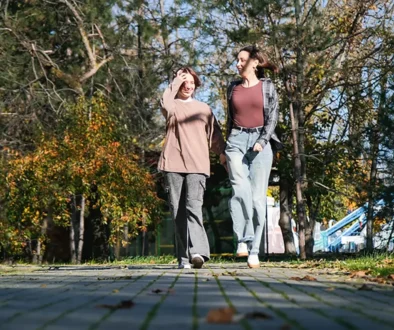 Žena jde během dne po parku vedle staršího dítěte