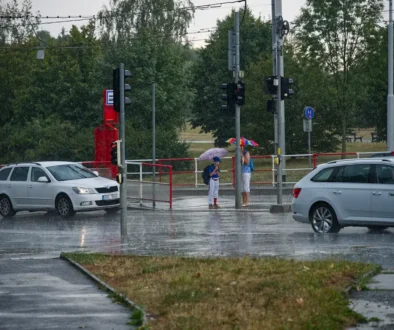 Deštivý den v hlavním městě České republiky a záběr na ulici s auty a lidmi s deštníky
