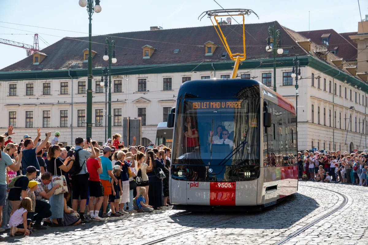 Zastávka s lidmi a přijíždějící tramvaj