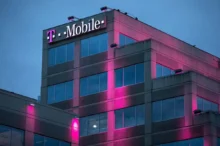 Růžově osvětlená budova mobilního operátora během večera