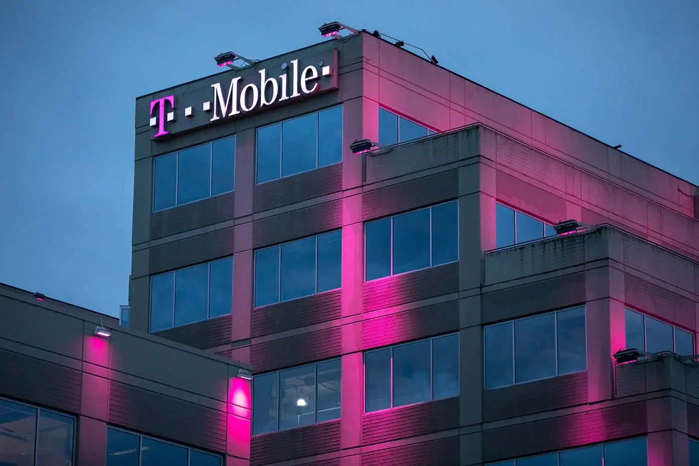 Růžově osvětlená budova mobilního operátora během večera