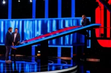 Tři muži stojí v tmavém studiu osvětleném modrým a červeným světlem