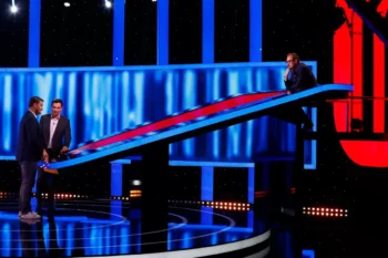 Tři muži stojí v tmavém studiu osvětleném modrým a červeným světlem