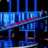 Tři muži stojí v tmavém studiu osvětleném modrým a červeným světlem