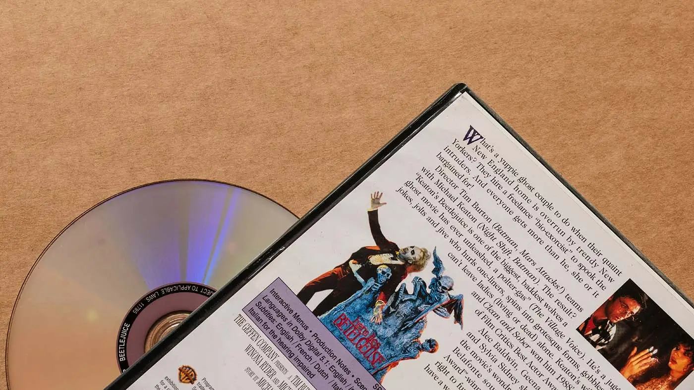 shutterstock_2690455813 | TVGURU.cz Na stole leží otevřená kniha s obrázky společně s nosičem DVD