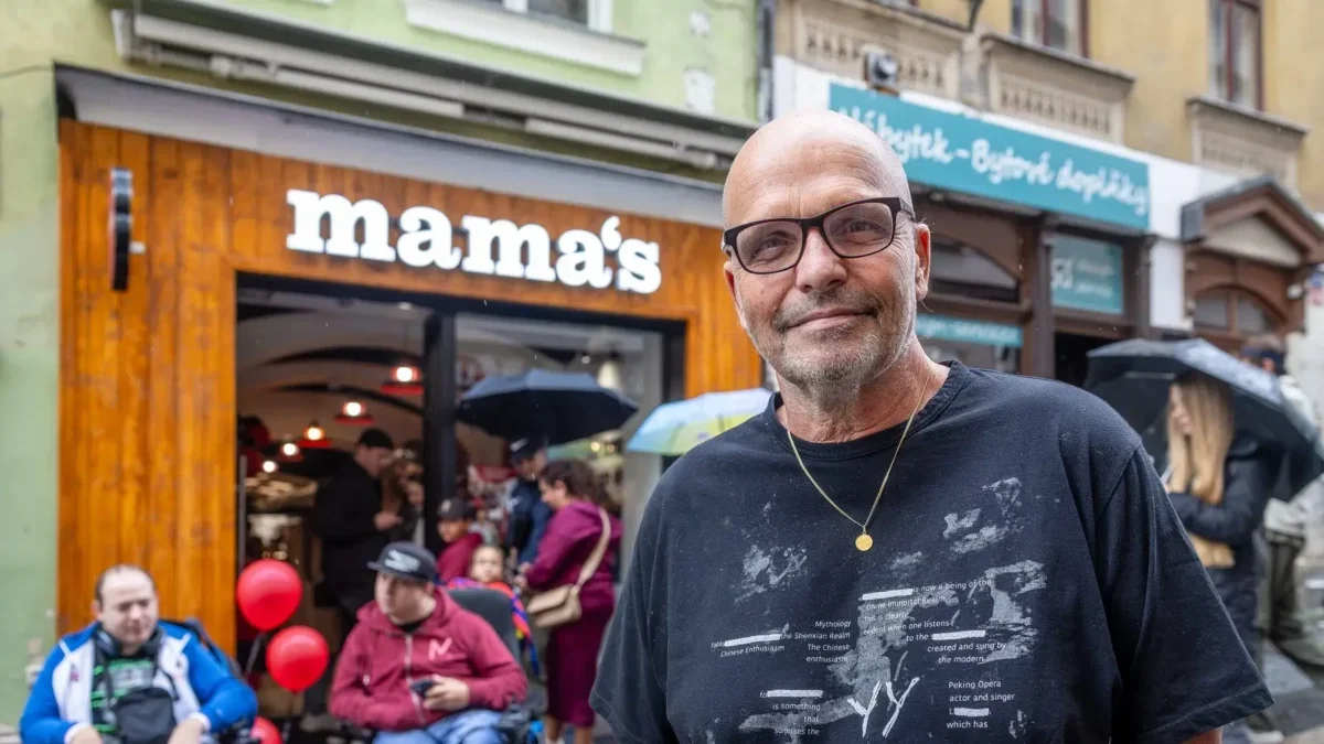 Muž v brýlích a černém triku před restaurací