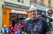 Muž v brýlích a černém triku před restaurací