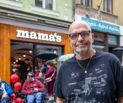 Muž v brýlích a černém triku před restaurací