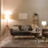 Teplé světlo osvětluje obývací pokoj s malou pohovkou a křeslem a pár doplňky