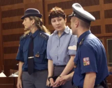 Policista a policistka zadržují ženu ve vězeňském oblečení a s pouty na rukou