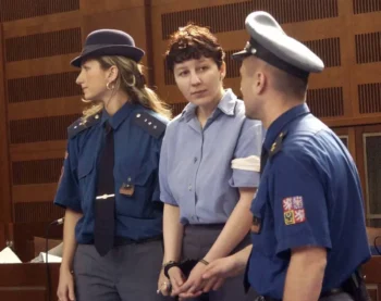 Policista a policistka zadržují ženu ve vězeňském oblečení a s pouty na rukou