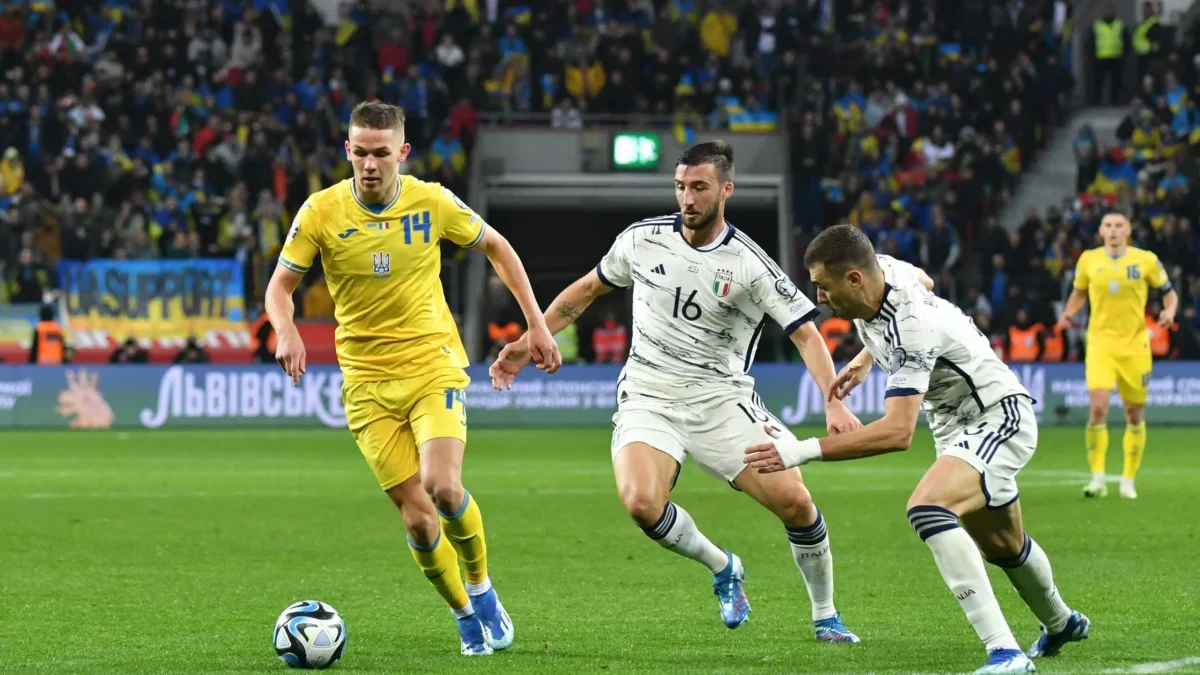 muži v dresech na trávníku kopou do míče