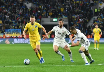 muži v dresech na trávníku kopou do míče
