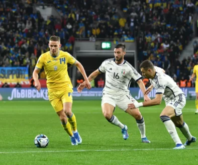 muži v dresech na trávníku kopou do míče