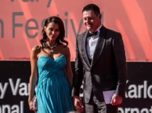 Muž v obleku a žena v šatech na červeném koberci