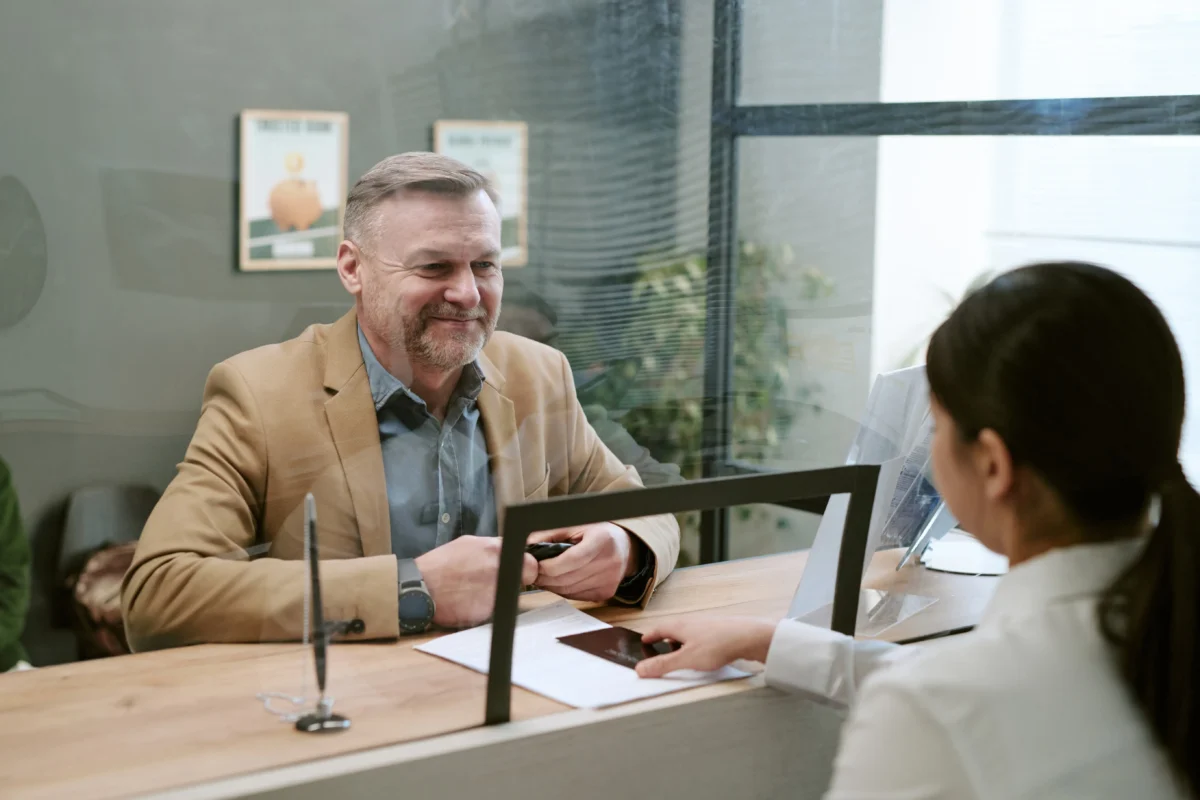 Banka potvrdila, že je muž v exekuci. Zdroj: Shutterstock | TVGURU.cz Muž sedící za přepážkou v bance