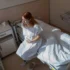 Žena sedí na posteli a vedle leží miminko.