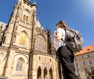 Žena s batohem stojí před katedrálou.