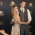 Smiling couple posing and dancing on a black backdrop with Star Dance and Česká televize logos; woman in a champagne dress and man in a gray vest and tie present on a red carpet backdrop.