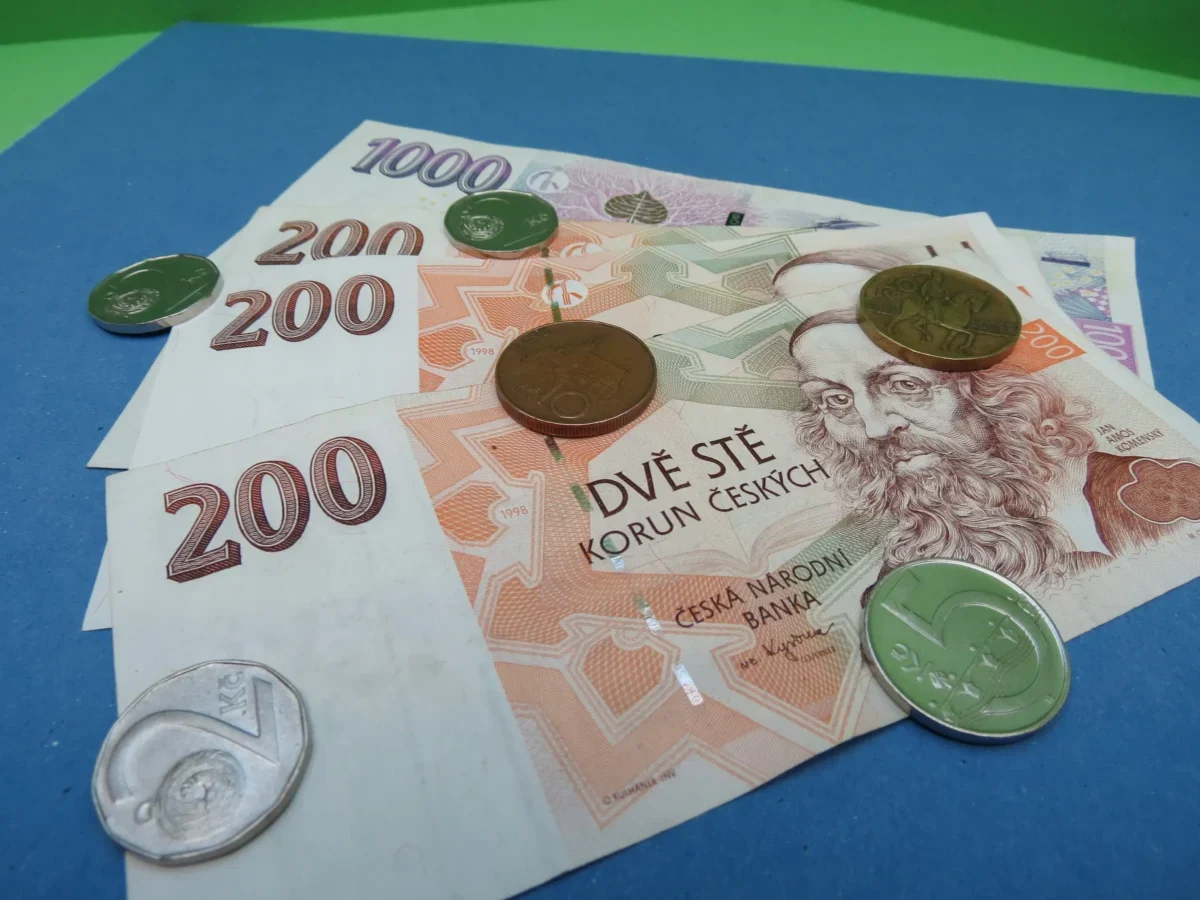 Na modrém podkladu leží české bankovky.