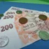 Na modrém podkladu leží české bankovky.