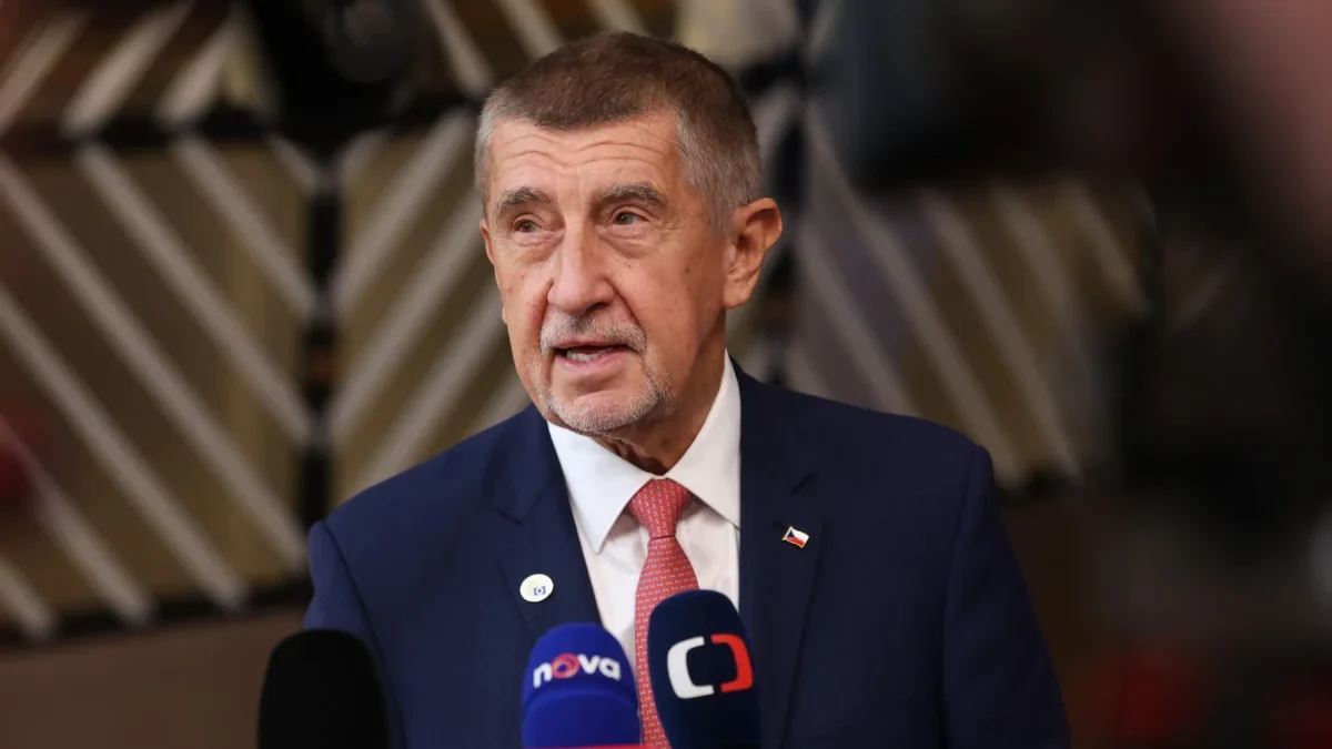 Premiér České republiky v obleku u mikrofonů.