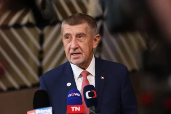Premiér České republiky v obleku u mikrofonů.