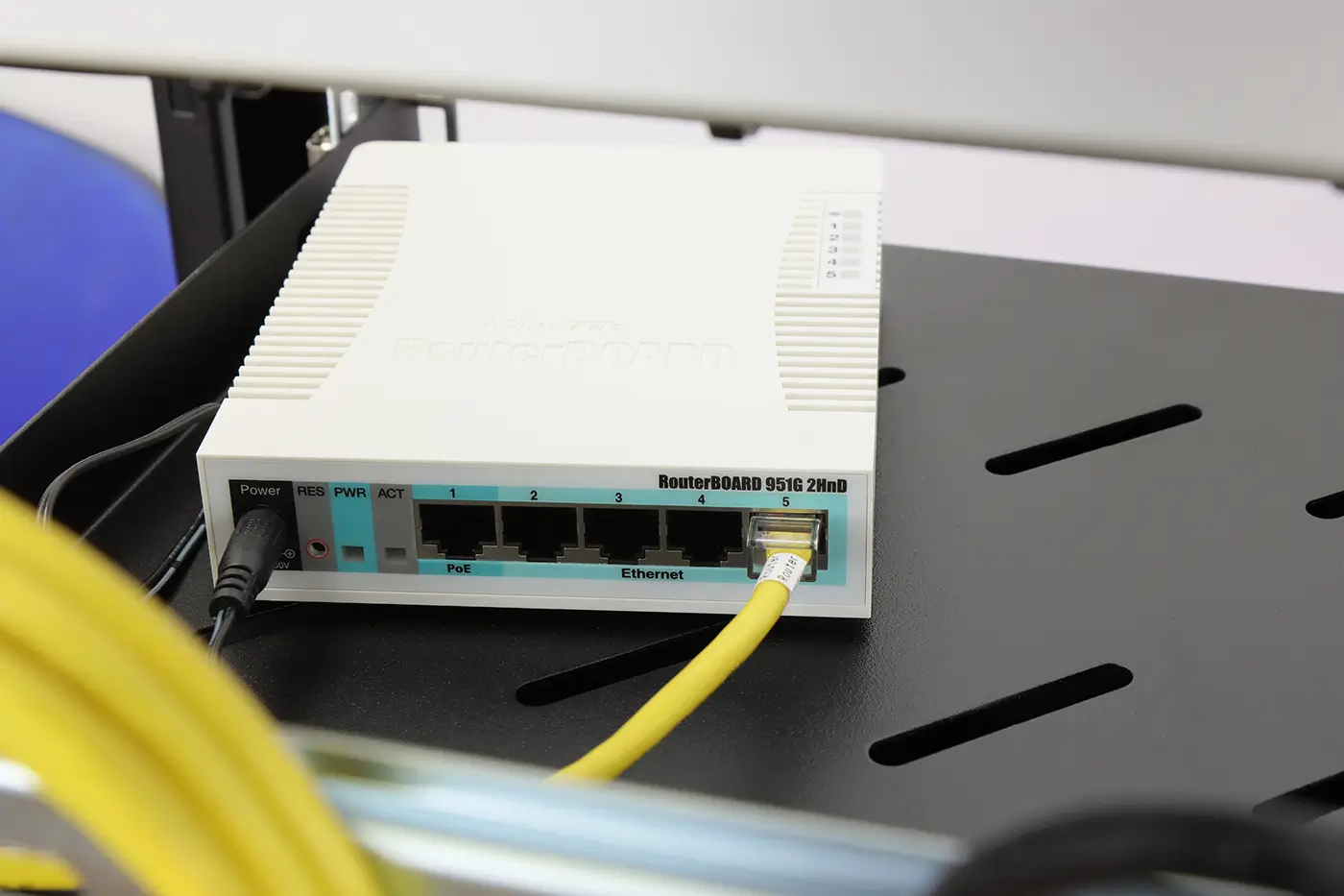 shutterstock_2241229999 | TVGURU.cz Na černé skříňce je položený bílý router se zapojeným žlutým kabelem