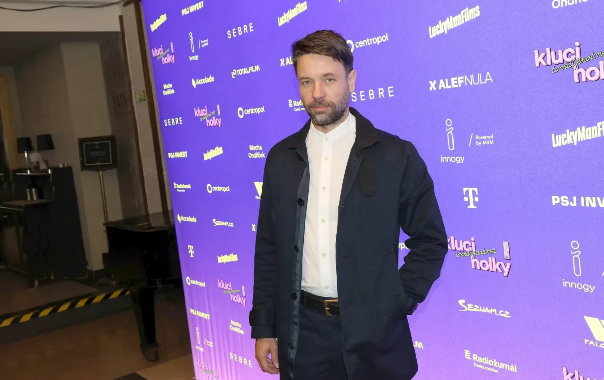 profimedia-1143105392 | TVGURU.cz Václav Neužil stojí před fialovým pozadím.