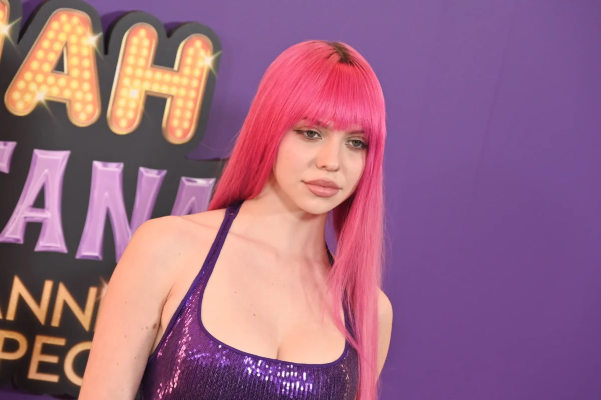 Zpěvačka ADÉLA stojí před nápisem Hannah Montana.