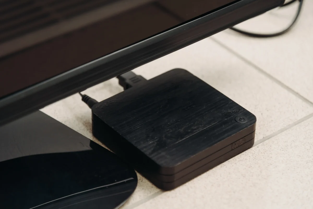 shutterstock_2853681251-2 | TVGURU.cz Pod obrazovkou leží set-top box.